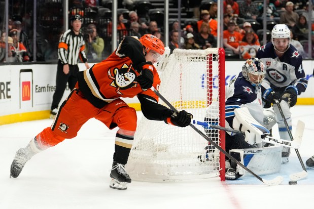 Ducks center Leo Carlsson, left, tries to get a shot...