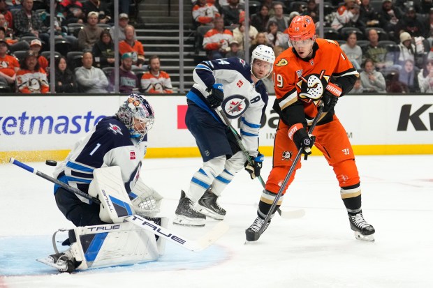 Winnipeg Jets goaltender Eric Comrie, left, is cored on Ducks...