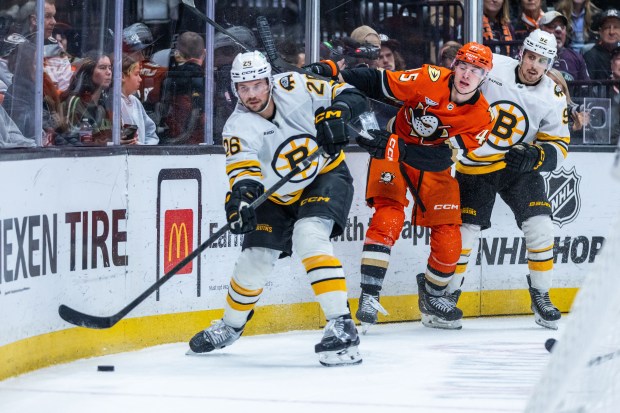 Boston Bruins defenseman Andrew Peekem left, and Ducks right wing...