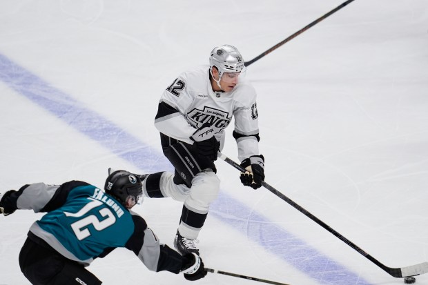 Kings left wing Trevor Moore, right, moves the puck while...