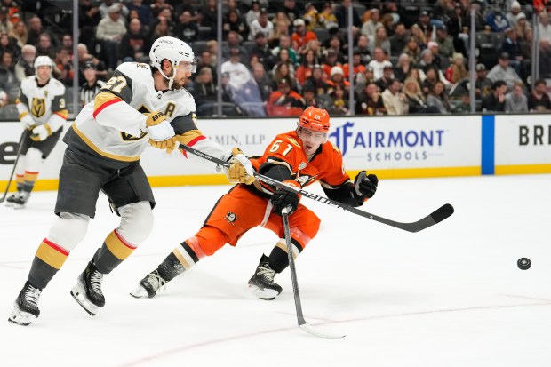 Vegas Golden Knights defenseman Shea Theodore, left passes the puck...