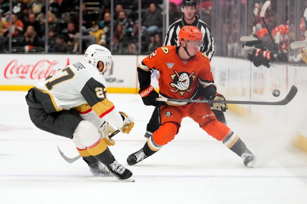 Anaheim Ducks defenseman Jackson LaCombe, right, tries to control the...
