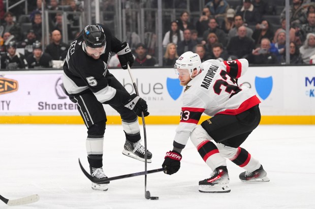 Kings defenseman Cody Ceci, left, shoots the puck as Ottawa...