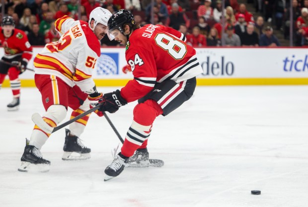 Blackhawks left wing Landon Slaggert (84) and Flames defenseman MacKenzie Weegar (52) chase the puck during the first period against the Calgary Flames, Nov. 18, 2025, at the United Center. (Dominic Di Palermo/Chicago Tribune)