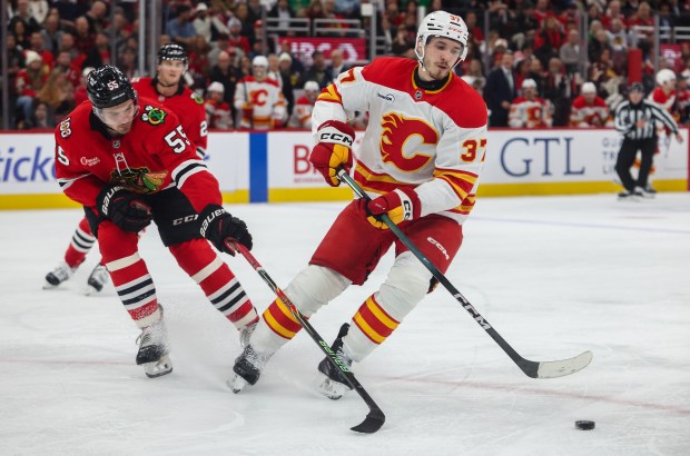 Blackhawks defenseman Artyom Levshunov (55) attempts to poke the puck away from Flames defenseman Yan Kuznetsov (37) during the second period, Nov. 18, 2025, at the United Center. (Dominic Di Palermo/Chicago Tribune)