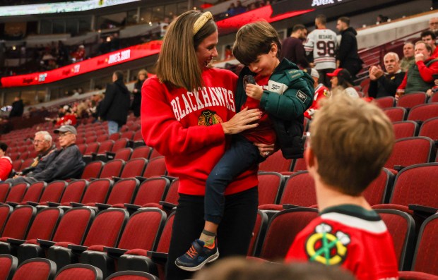 Mallory Guerreso of Beverly (CQ) shows her son Tony Guerreso, 4, (CQ) a puck they received from Flames defenseman Rasmus Andersson (4) before a game between the Blackhawks and Calgary Flames, Nov. 18, 2025, at the United Center. (Dominic Di Palermo/Chicago Tribune)