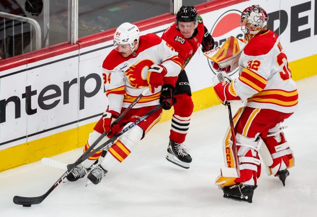 Blackhawks center Oliver Moore (11) tries to steal the puck away from Flames defenseman Brayden Pachal (94) during the third period, Nov. 18, 2025, at the United Center. (Dominic Di Palermo/Chicago Tribune)