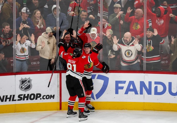 Blackhawks center Oliver Moore (11) and Blackhawks center Frank Nazar (91) celebrate his goal that brought the Blackhawks up 4-2 during the third period against the Calgary Flames, Nov. 18, 2025, at the United Center. (Dominic Di Palermo/Chicago Tribune)