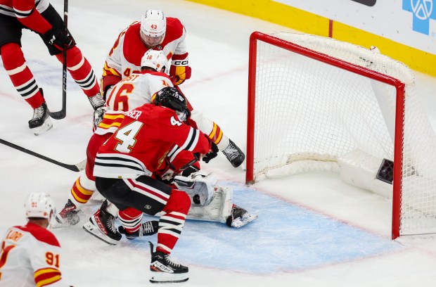 Blackhawks goaltender Arvid Soderblom (40) makes a save while Flames right wing Adam Klapka (43) and Flames center Morgan Frost (16) try to put the puck in the goal during the third period, Nov. 18, 2025, at the United Center. (Dominic Di Palermo/Chicago Tribune)
