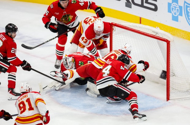 Blackhawks goaltender Arvid Soderblom (40) makes a save while Flames right wing Adam Klapka (43) and Flames center Morgan Frost (16) try to put the puck in the goal during the third period, Nov. 18, 2025, at the United Center. (Dominic Di Palermo/Chicago Tribune)