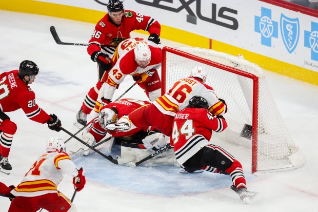 Blackhawks goaltender Arvid Soderblom (40) makes a save while Flames right wing Adam Klapka (43) and Flames center Morgan Frost (16) try to put the puck in the goal during the third period, Nov. 18, 2025, at the United Center. (Dominic Di Palermo/Chicago Tribune)