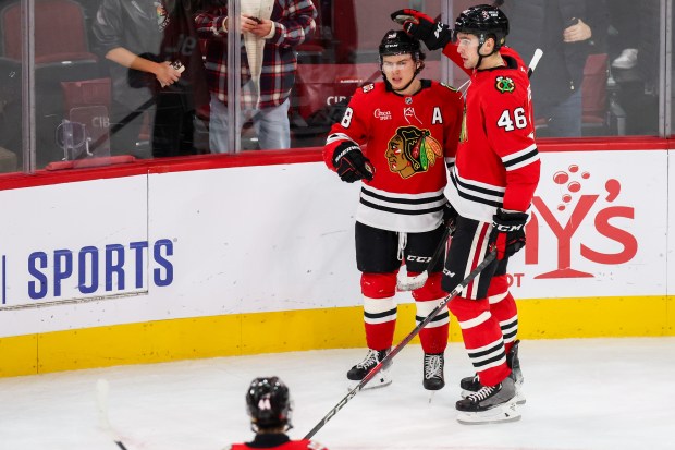 Blackhawks defenseman Louis Crevier (46) congratulates Blackhawks center Connor Bedard (98) on his third goal that brought the Blackhawks up 5-2 during the third period against the Calgary Flames, Nov. 18, 2025, at the United Center. (Dominic Di Palermo/Chicago Tribune)