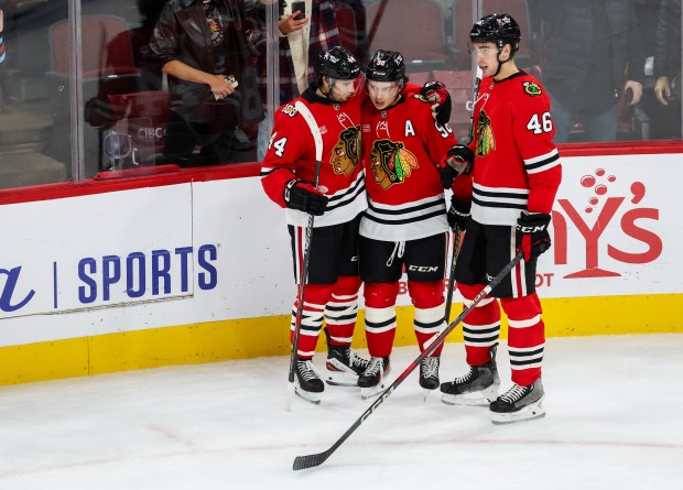 Blackhawks defenseman Louis Crevier (46) and Blackhawks defenseman Wyatt Kaiser (44) congratulate Blackhawks center Connor Bedard (98) on his third goal that brought the Blackhawks up 5-2 during the third period against the Calgary Flames, Nov. 18, 2025, at the United Center. (Dominic Di Palermo/Chicago Tribune)