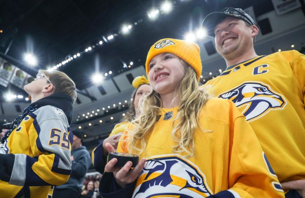 Savannah Suchy, 10, of Fort Atkinson, Wisconsin smiles after receiving a puck from Nashville Predators right wing Luke Evangelista while her dad Michael Suchy looks on before a game against the Blackhawks, Nov. 28, 2025, at the United Center. (Dominic Di Palermo/Chicago Tribune)