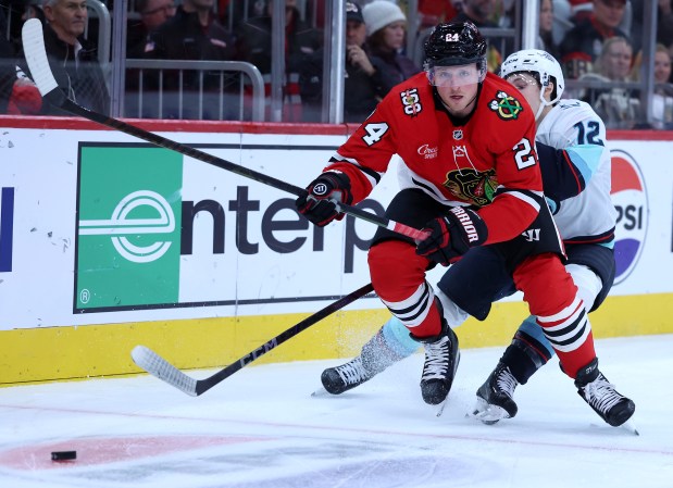 Chicago Blackhawks center Sam Lafferty (24) and Seattle Kraken left wing Tye Kartye (12) battle in the first period of a game at the United Center in Chicago on Nov. 20, 2025. (Chris Sweda/Chicago Tribune)