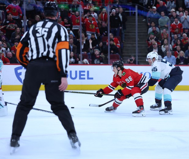 A referee watches as Chicago Blackhawks center Connor Bedard (98) fails to score as Seattle Kraken defenseman Ryan Lindgren (55) trails on the play in the third period of a game at the United Center in Chicago on Nov. 20, 2025. (Chris Sweda/Chicago Tribune)