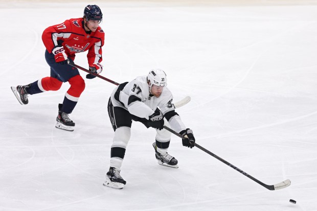 The Kings’ Warren Foegele, right, passes the puck as the...