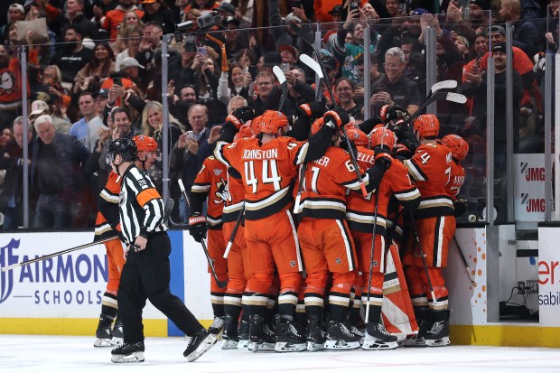 Teammates surround the Ducks’ Olen Zellweger after his overtime goal...