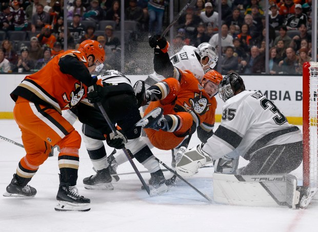 The Ducks’ Ross Johnston (44) is knocked off balance by...