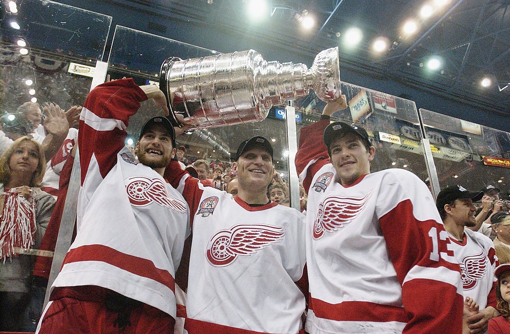Boyd Devereaux #21 (L), Brett Hull #17 (C) and Pavel Datsyuk #13 (R) of the Detroit Red Wings raise the Stanley Cup after eliminating the Carolina Hurricanes in Game 5 of the 2002 NHL Stanley Cup Final. (Elsa/Getty Images/NHLI)