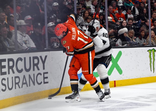 The Kings’ Corey Perry, right, tries to get the puck...