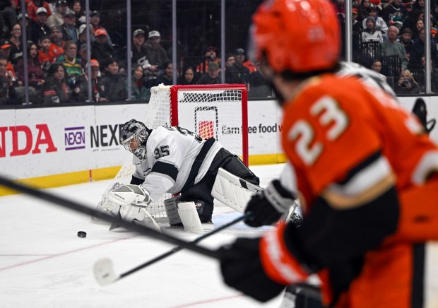 Kings goaltender Darcy Kuemper, left, dives for the puck during...