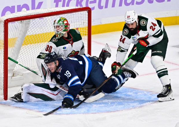 Minnesota Wild Zach Bogosian (24) dumps Winnipeg Jets' Jonathan Toews (19) in front of his goaltender Jesper Wallstedt (30) during the first period of an NHL hockey game in Winnipeg, Manitoba, Sunday Nov. 23, 2025. (Fred Greenslade/The Canadian Press via AP)