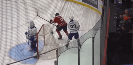 Hockey players near the goal, with a goalie in front.