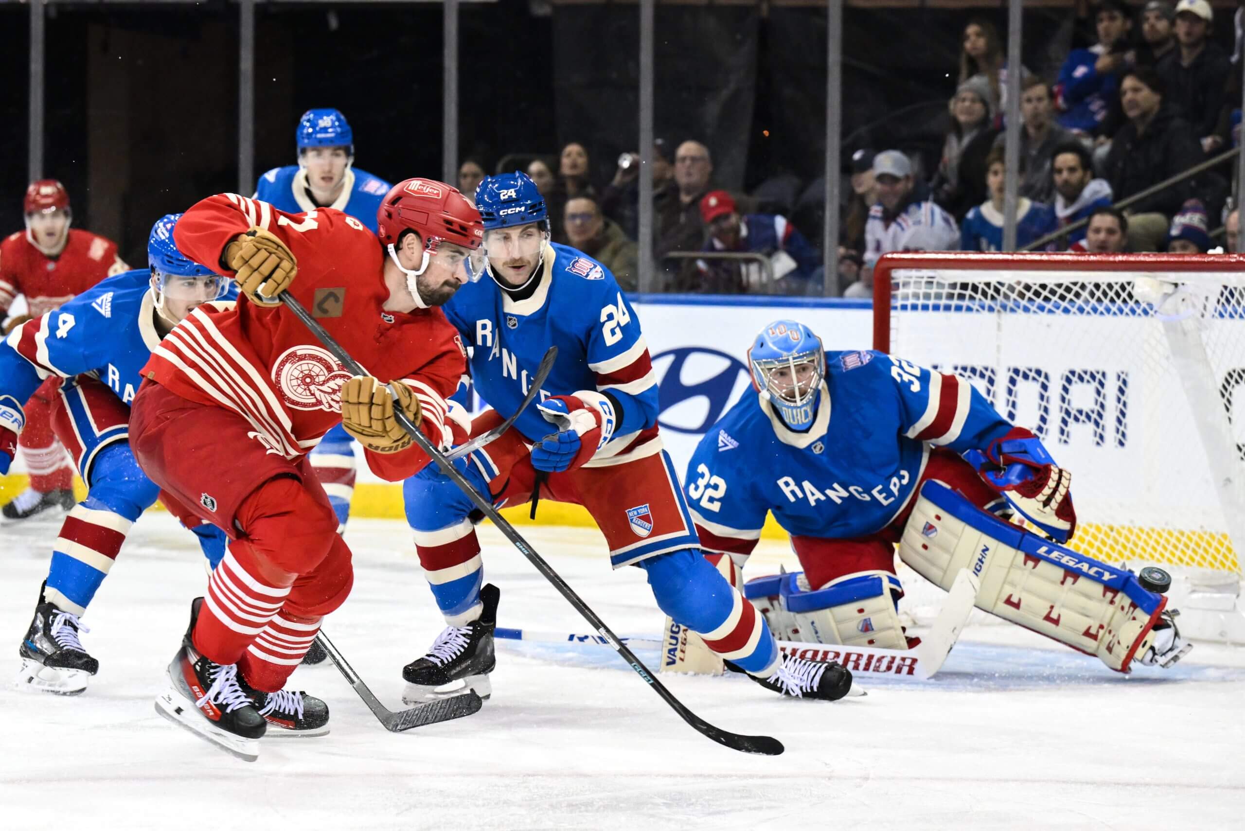 Two Rangers defensemen try to block Detroit's Dylan Larkin from shooting on Jonathan Quick.