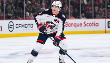 Kirill Marchenko, charlie Coyle and Elvis Merzlikins with the Blue Jackets logo in the background.