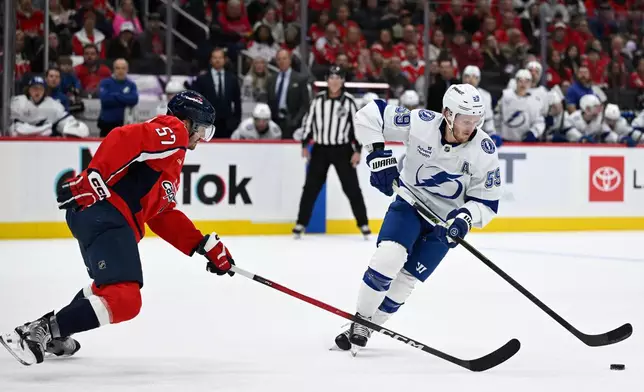 Tampa Bay Lightning center Jake Guentzel, right, gathers a loose puck against Washington Capitals defenseman Trevor van Riemsdyk during the second period of an NHL hockey game, Saturday, Nov. 22, 2025, in Washington. (AP Photo/John McDonnell)