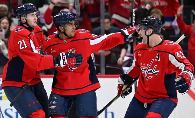 Washington Capitals right wing Justin Sourdif, center, celebrates his goal with Capitals center Aliaksei Protas (21) and Capitals right wing Tom Wilson during the first period of an NHL hockey game against the Tampa Bay Lightning, Saturday, Nov. 22, 2025, in Washington. (AP Photo/John McDonnell)