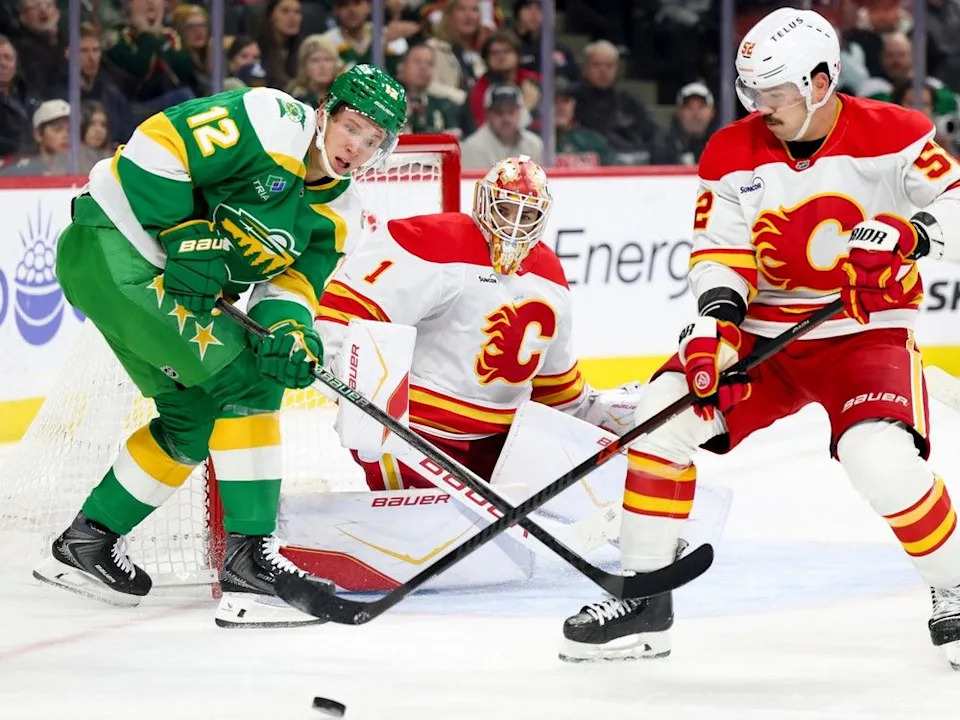  Flames defenceman Mackenzie Weegar works the puck away from Wild forward Matt Boldy while Flames goaltender Devin Cooley keeps watch during Sunday’s game.