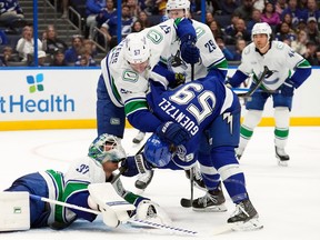 Kevin Lankinen has his mask lifted as Tampa Bay's Jake Guentzel and Tyler Myers jostle in front of the net during the second period