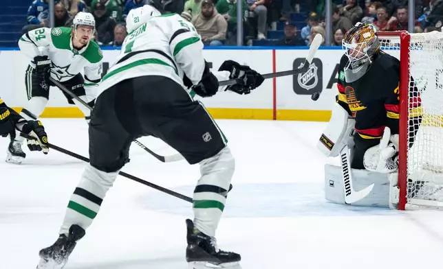 Vancouver Canucks goaltender Kevin Lankinen (32) stops Dallas Stars' Jason Robertson (21) as Roope Hintz (24) watches during the first period of an NHL hockey game in Vancouver, Thursday, Nov. 20, 2025. (Ethan Cairns/The Canadian Press via AP)