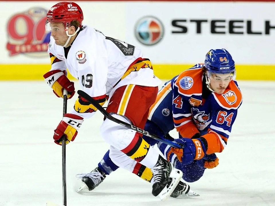  Calgary Wranglers rookie Andrew Basha protects the puck from Connor Clattenburg of the Bakersfield Condors. Photo by David Moll, courtesy of Calgary Wranglers