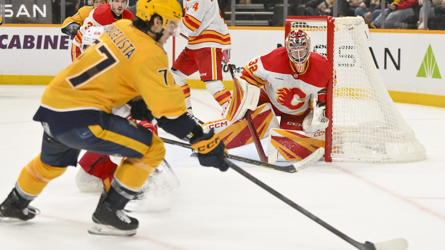 Dec 2, 2025; Nashville, Tennessee, USA;  Calgary Flames goaltender Dustin Wolf (32) blocks the shot of Nashville Predators right wing Luke Evangelista (77) during the third period at Bridgestone Arena. Mandatory Credit: Steve Roberts-Imagn Images