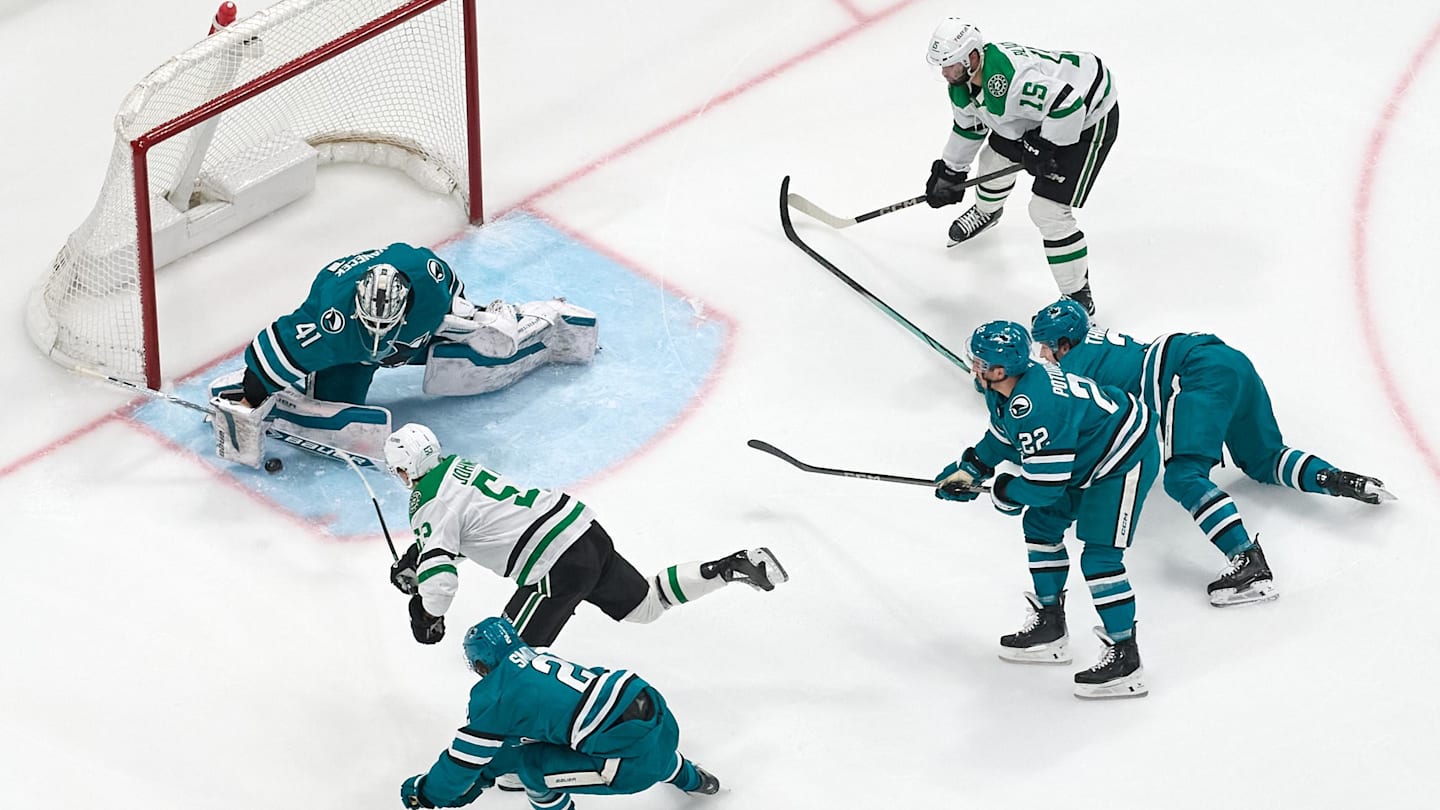 Feb 8, 2025; San Jose, California, USA; Dallas Stars center Colin Blackwell (15) looks on as center Wyatt Johnston (53) shoots the puck against San Jose Sharks goaltender Vitek Vanecek (41), defenseman Henry Thrun (3), and centers Will Smith (2) and Andrew Poturalski (22) during the third period at SAP Center at San Jose. Mandatory Credit: Robert Edwards-Imagn Images