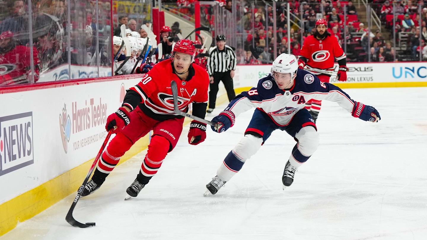 Jan 23, 2025; Raleigh, North Carolina, USA;  Carolina Hurricanes center Sebastian Aho (20) and Columbus Blue Jackets defenseman Zach Werenski (8) chase after the puck during the first period at Lenovo Center. Mandatory Credit: James Guillory-Imagn Images