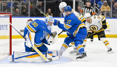 Dec 9, 2025; St. Louis, Missouri, USA; St. Louis Blues goaltender Joel Hofer (30) and defenseman Cam Fowler (17) defend the net against Boston Bruins center Casey Mittelstadt (11) during the first period at Enterprise Center. Mandatory Credit: Jeff Curry-Imagn Images