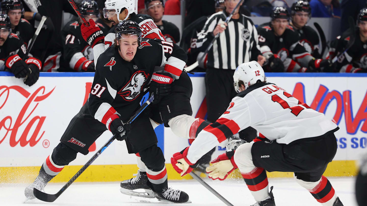 Nov 28, 2025; Buffalo, New York, USA;  Buffalo Sabres right wing Josh Doan (91) plays the puck as New Jersey Devils center Cody Glass (12) defends during the second period at KeyBank Center. Mandatory Credit: Timothy T. Ludwig-Imagn Images