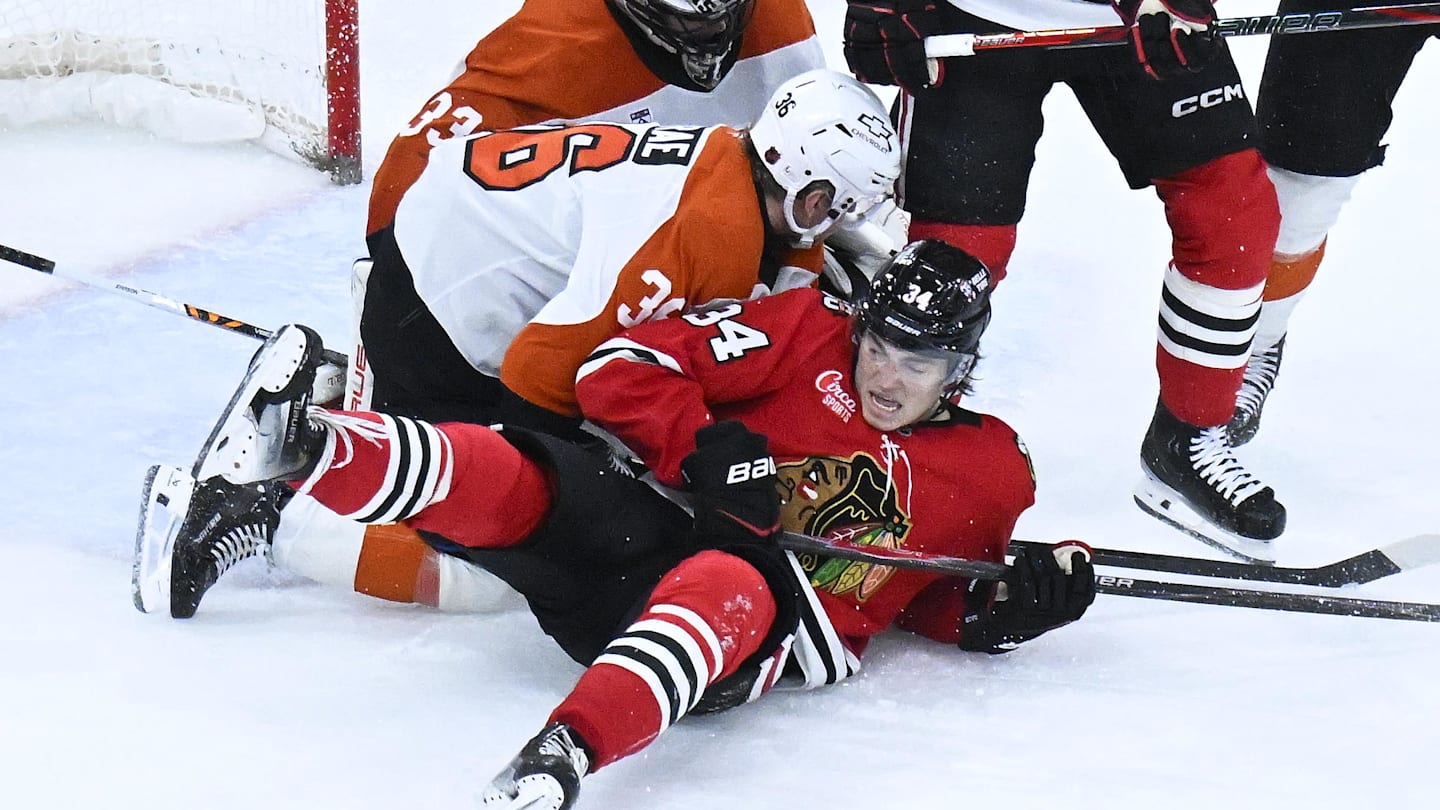 Dec 23, 2025; Chicago, Illinois, USA;  Chicago Blackhawks center Colton Dach (34) fight for the puck with Philadelphia Flyers defenseman Emil Andrae (36) during the third period at United Center. Mandatory Credit: Matt Marton-Imagn Images
