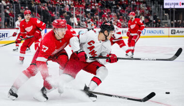 Apr 4, 2025; Detroit, Michigan, USA; Detroit Red Wings defenseman Simon Edvinsson (77) and Carolina Hurricanes center Jesperi Kotkaniemi (82) battle for the puck during the third period at Little Caesars Arena. Mandatory Credit: Tim Fuller-Imagn Images