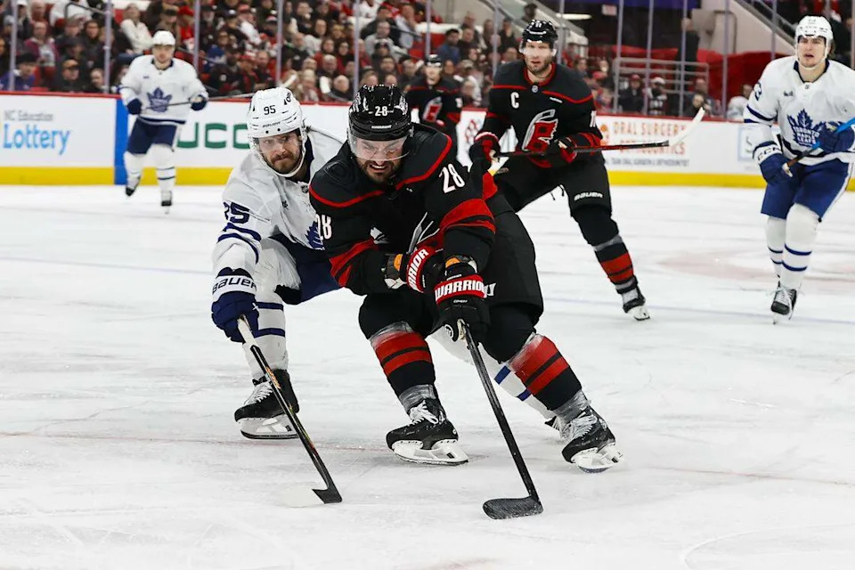William Carrier (28) of the Carolina Hurricanes skates with the puck guarded by Oliver Ekman-Larsson of the Toronto Maple Leafs during the second period game at Lenovo Center on Dec. 4, 2025 in Raleigh, North Carolina.