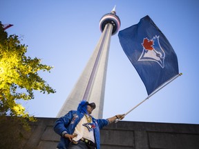 Blue Jays fan Tadziu Krawiec waves a flag outside the Rogers Centre ahead of Game 7 of the World Series.