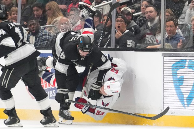 Kings defenseman Joel Edmundson, center, collides with Washington Capitals center...