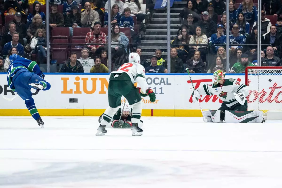 Vancouver Canucks Aatu Raty, left, scores on Minnesota Wild goaltender Jesper Wallstedt (30) during second period NHL hockey action in Vancouver on Saturday, Dec. 6, 2025. (Ethan Cairns/The Canadian Press via AP)
