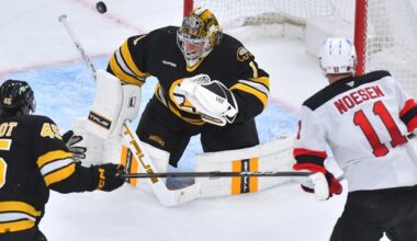 Boston Bruins goaltender Jeremy Swayman (1) deflects the puck as New Jersey Devils right wing Stefan Noesen (11) is unable to score as defenseman Jonathan Aspirot (45) looks on in the second period of an NHL hockey game, Saturday, Dec. 6, 2025, in Boston. (AP Photo/Steven Senne)