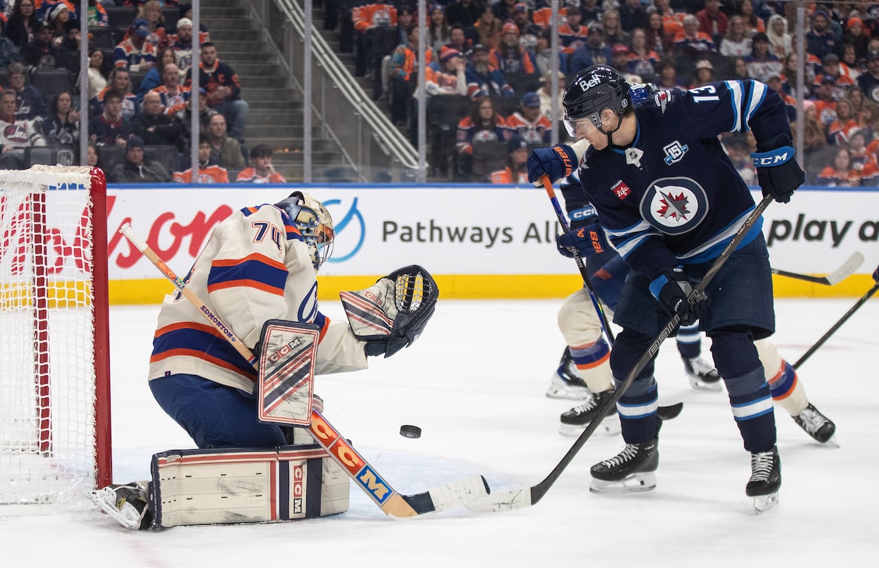 A hockey player shoots the puck on net at a goalie.