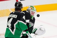 Dallas Stars goaltender Jake Oettinger (29) defends against a shot as Miro Heiskanen (4)...